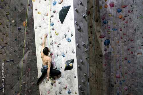 Rock climber high on an indoor climbing wall photo