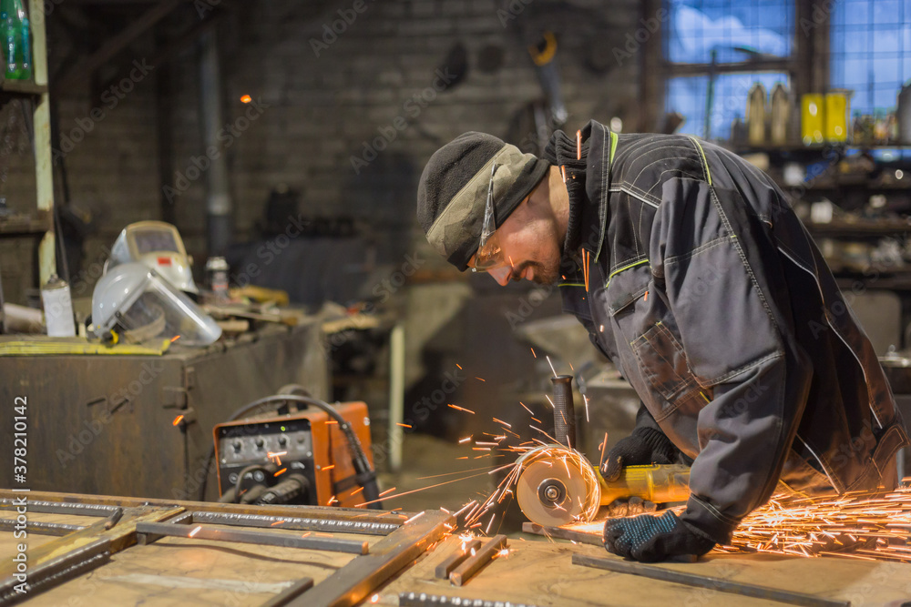 Professional blacksmith sawing metal with hand circular saw at forge, workshop. Handmade, craftsmanship and blacksmithing concept Professional blacksmith sawing metal with hand circular saw at forge, workshop. Handmade, craftsmanship and blacksmithing concept