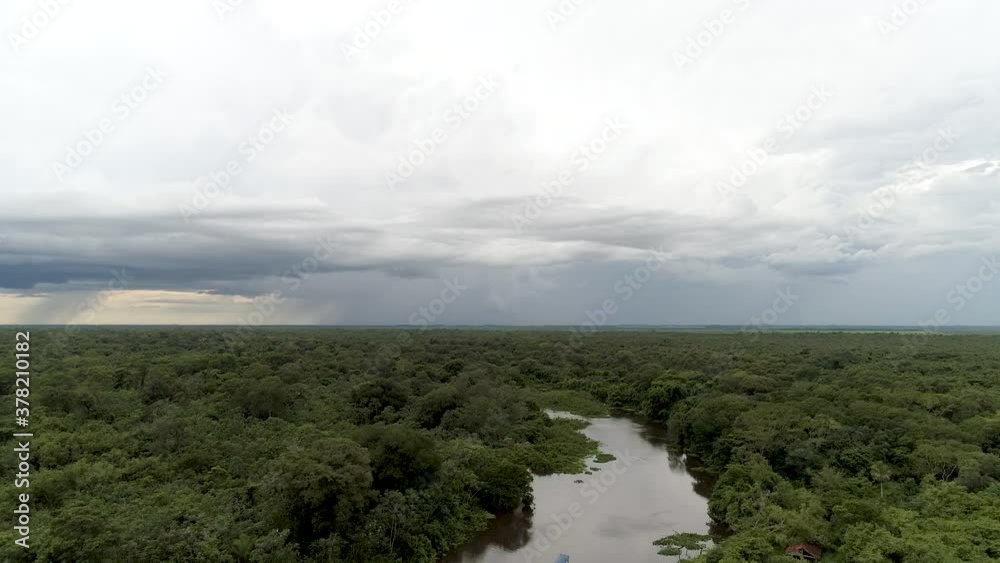 Aerial view overlooking a ferry on a river, surrounded by tropical wetlands and Jungle, dark, cloudy day, in Pantanal Conservation Area, Brazil - descending, drone shot Aerial view overlooking a ferry on a river, surrounded by tropical wetlands and Jungle, dark, cloudy day, in Pantanal Conservation Area, Brazil - descending, drone shot
