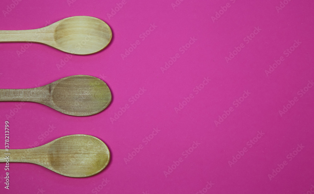 High angle view on three wood spoons on pink background with blank copy space for text High angle view on three wood spoons on pink background with blank copy space for text