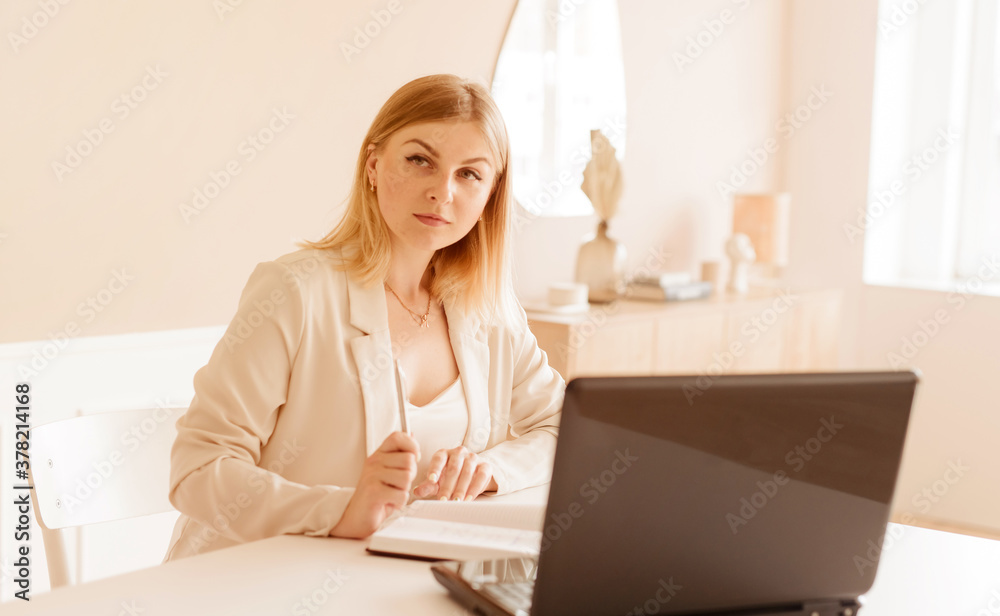 Portrait of a serious business woman with a laptop sitting at the table in the living room while working at home Portrait of a serious business woman with a laptop sitting at the table in the living room while working at home