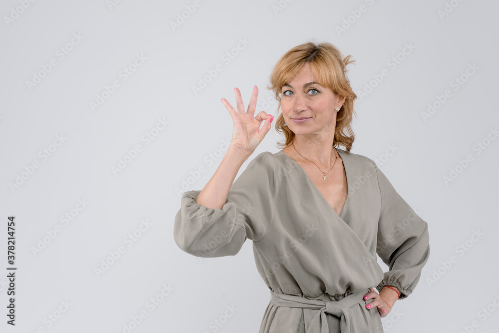 Beautiful smiling woman showing okey sign, looking to the camera, isolated on white studio background Beautiful smiling woman showing okey sign, looking to the camera, isolated on white studio background