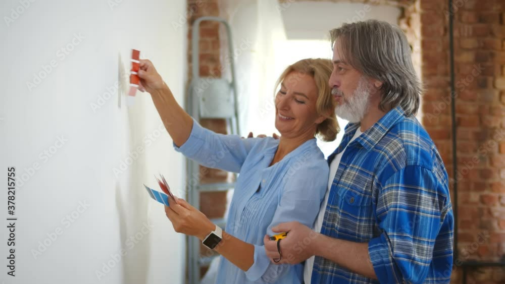Senior couple with color swatch choosing painting for new home