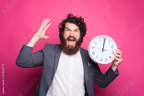 Portrait of angry business man screaming and holding CLOCK, delay concept © Vulp