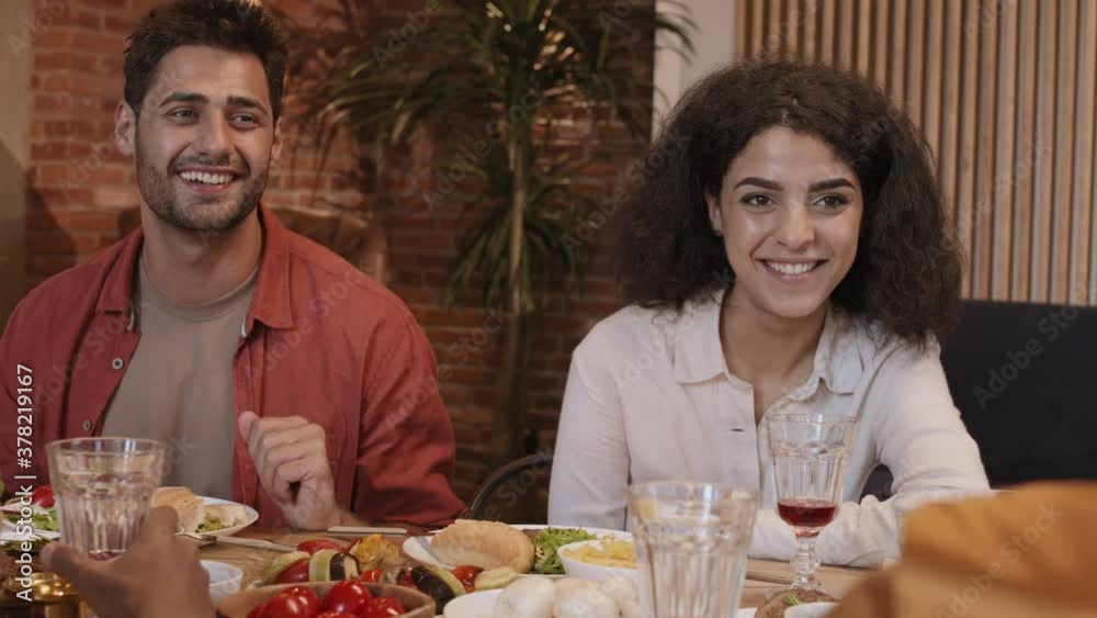 Rear view of two diverse young women and mixed-race handsome man are sitting together at dining table in cafe and having pleasant talk Rear view of two diverse young women and mixed-race handsome man are sitting together at dining table in cafe and having pleasant talk