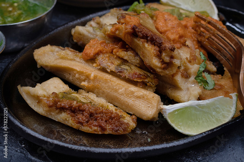 Fried vegan tamales in cast iron serving plate along with ranchero sauce and chili cilantrio salsa