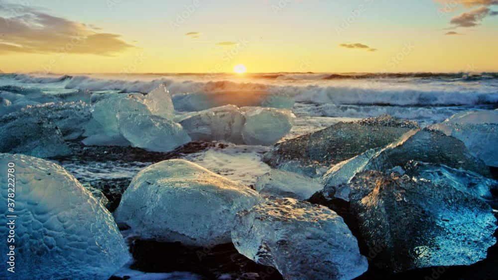 Slow motion waves on icy Okulsarlon Beach at sunset, close up