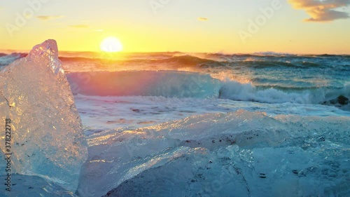 Waves lap in slow motion onto Okulsarlon Beach at sunset, close up