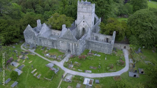 Tourist walks through graveyard and church ruins in Ireland, aerial