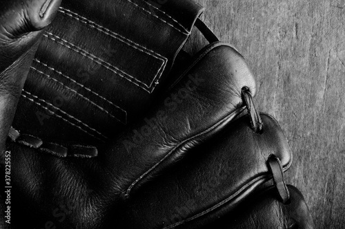 Old leather baseball glove texture close up in black and white.
