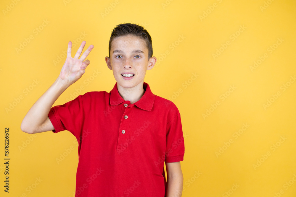 Young beautiful child boy over isolated yellow background doing ok sign with fingers and smiling, excellent symbol Young beautiful child boy over isolated yellow background doing ok sign with fingers and smiling, excellent symbol