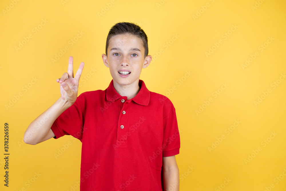 Young beautiful child boy over isolated yellow background showing and pointing up with fingers number two while smiling confident and happy Young beautiful child boy over isolated yellow background showing and pointing up with fingers number two while smiling confident and happy