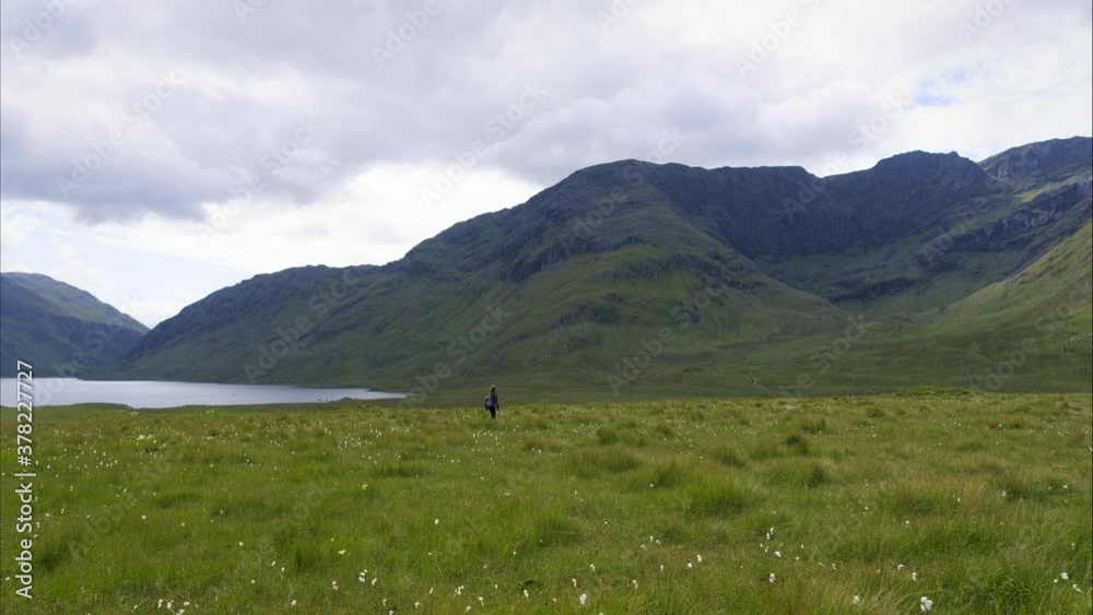 Woman walks through Ireland mountains, wide aerial Woman walks through Ireland mountains, wide aerial