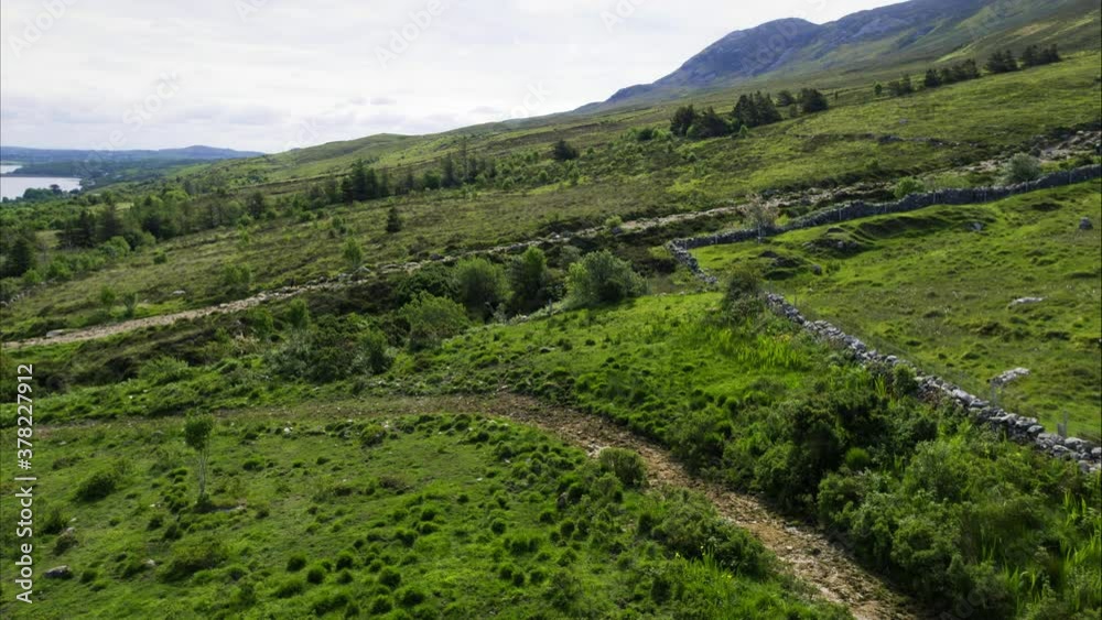 Pan right aerial, woman hikes up hillside in Ireland Pan right aerial, woman hikes up hillside in Ireland