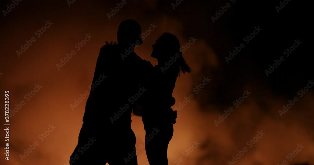 Embracing couple in front of lava flow at night, wide Embracing couple in front of lava flow at night, wide