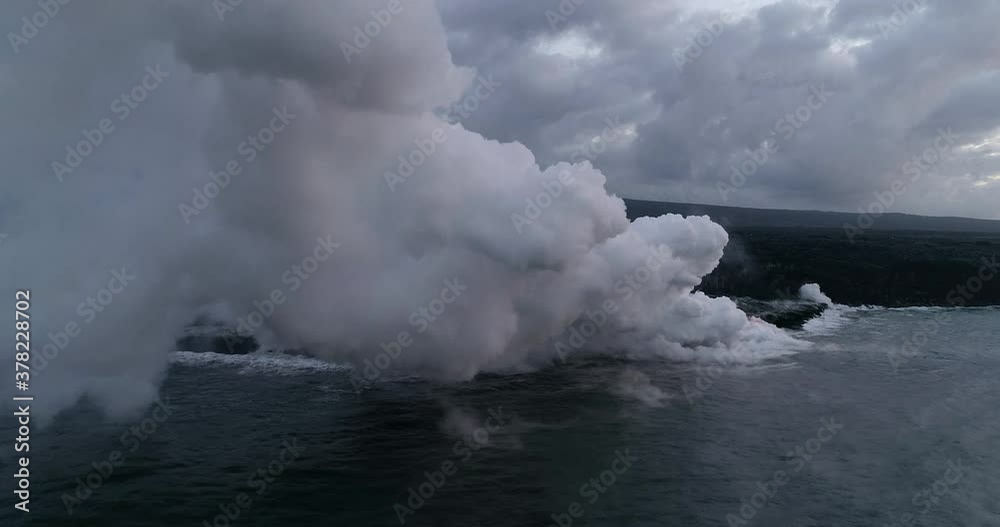 Slow motion aerial, rising steam from lava flow into ocean Slow motion aerial, rising steam from lava flow into ocean