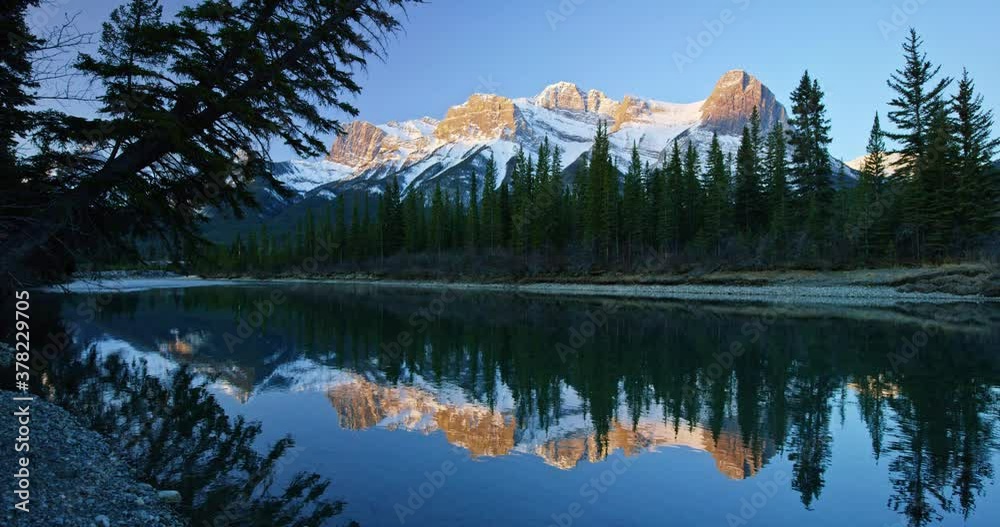 Mountains reflect off creek in Banff National Park, low angle
