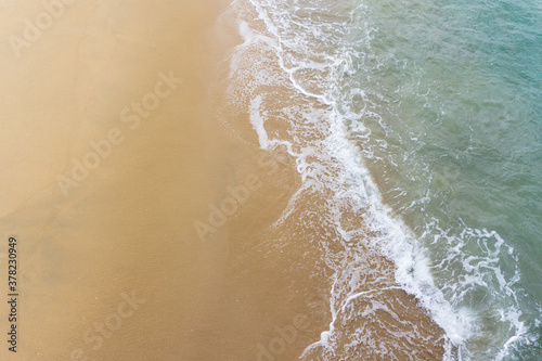 Fototapeta Naklejka Na Ścianę i Meble -  High angle view of ocean waves washing up onto sandy beach