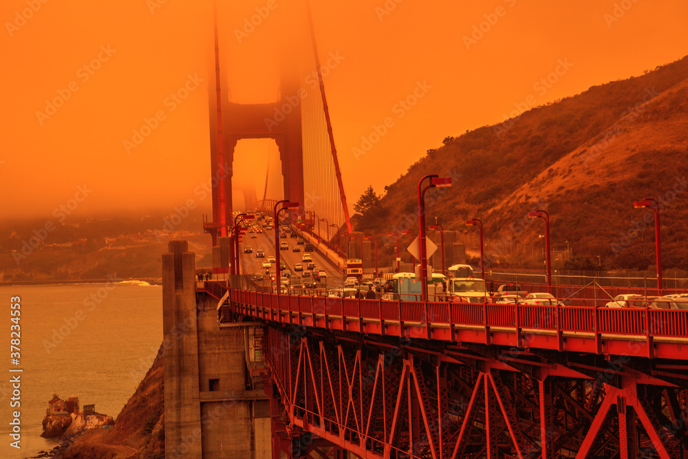 Cars crossing Golden Gate Bridge from Lime point. Smoky orange sky the bridge of San Francisco city for California fires in September 2020 in America. Wildfires composition.