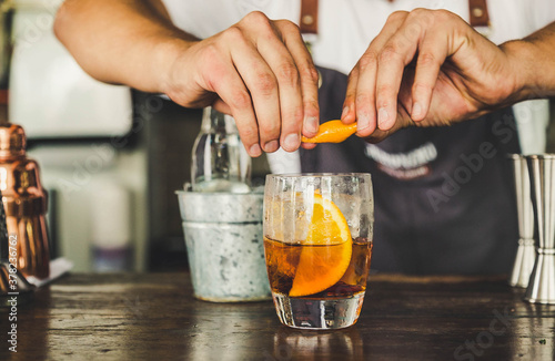 Man's hands pouring vermouth into the glass from a pitcher. Bar from a bar.