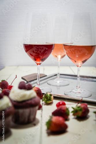 Three wines in a glass with fruit on a white table.