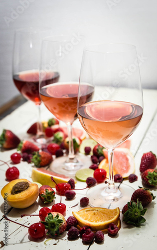 Three wines in a glass with fruit on a white table.