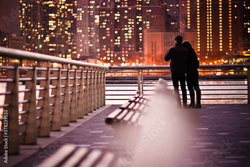 Couple standing by the river at night with bokeh lights in front love