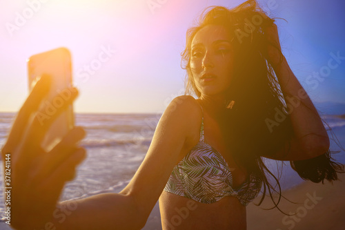 Women taking selfie and having fun on the sunset beach