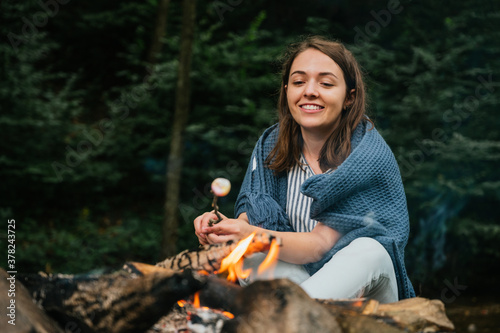 Beautiful young woman roasting marshmallows over a campfire photo