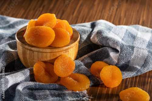 Dried apricots in bowl on fabric photo