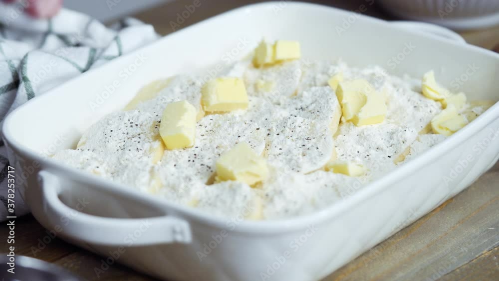 Preparing scalloped potatoes in a white ceramic baking dish. Preparing scalloped potatoes in a white ceramic baking dish.