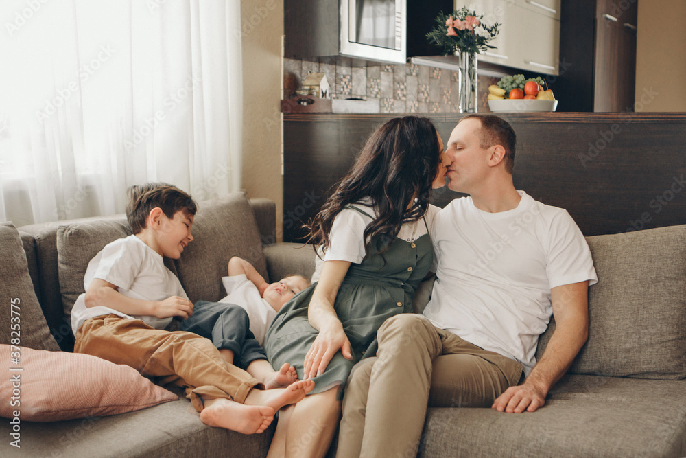 Obraz premium A family with two children is sitting on the sofa. Weekend at home. Spending time together