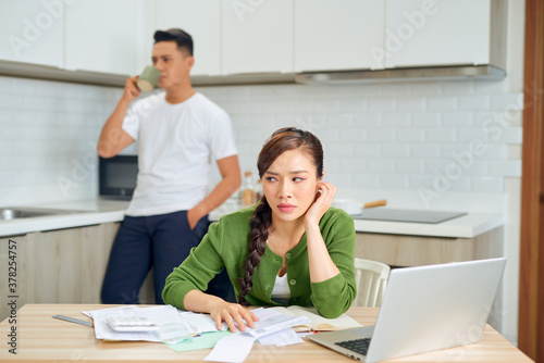 Upset young man with financial bills having conflict with woman at home