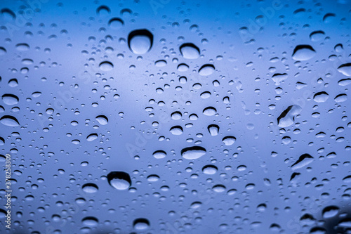 gotas de lluvia sobre el cristal, con el cielo azul de fondo photo