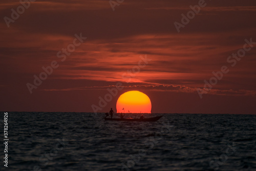 Fototapeta Naklejka Na Ścianę i Meble -  Blur boat passed by the big sun on the sea