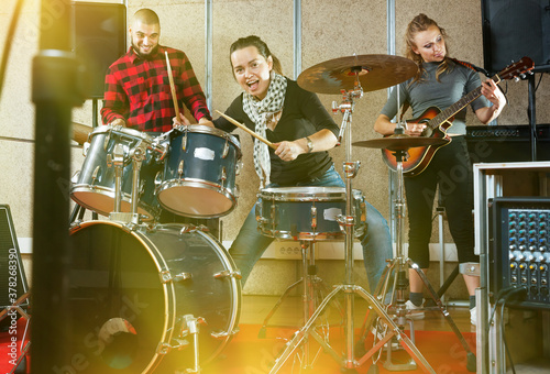 Rehearsal of music group. Rock band with emotional female drummer playing in the recording studio