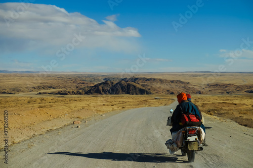 Mongolian riding motorcycle in Bayankhongor road during autumn, Mongolia.  photo