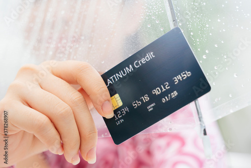 Woman hand with shopping credit card in rainy season.