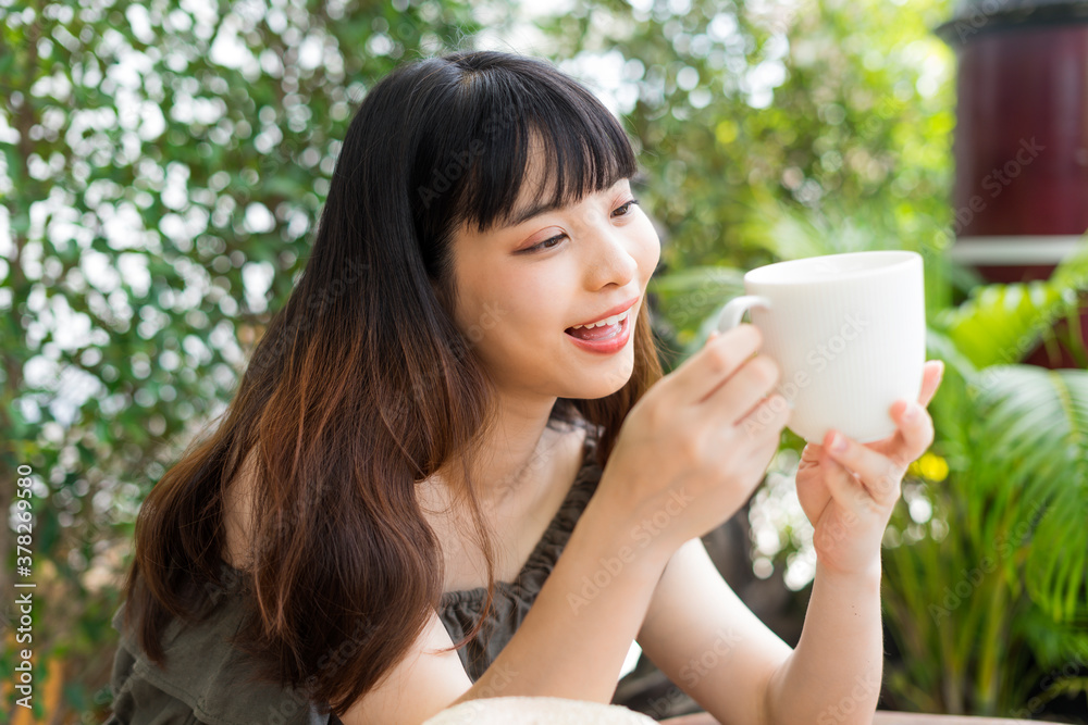 Young asian woman holding a cup of coffee at cafe outdoors. Young asian woman holding a cup of coffee at cafe outdoors.