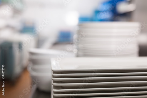 Closeup of clean white plates stacked on table in restaurant kitchen..