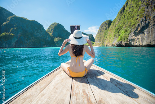 View of woman in swimsuit enjoying on thai traditional longtail Boat over beautiful mountain and ocean, Phi phi Islands, Thailand