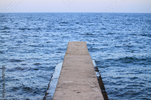 Grey stone old pier in the deep blue sea
