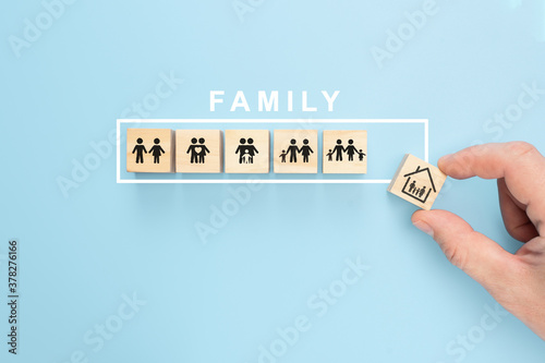 Hand arranging wood cube with family symbol on pastel blue background, copy space. Family Concept background