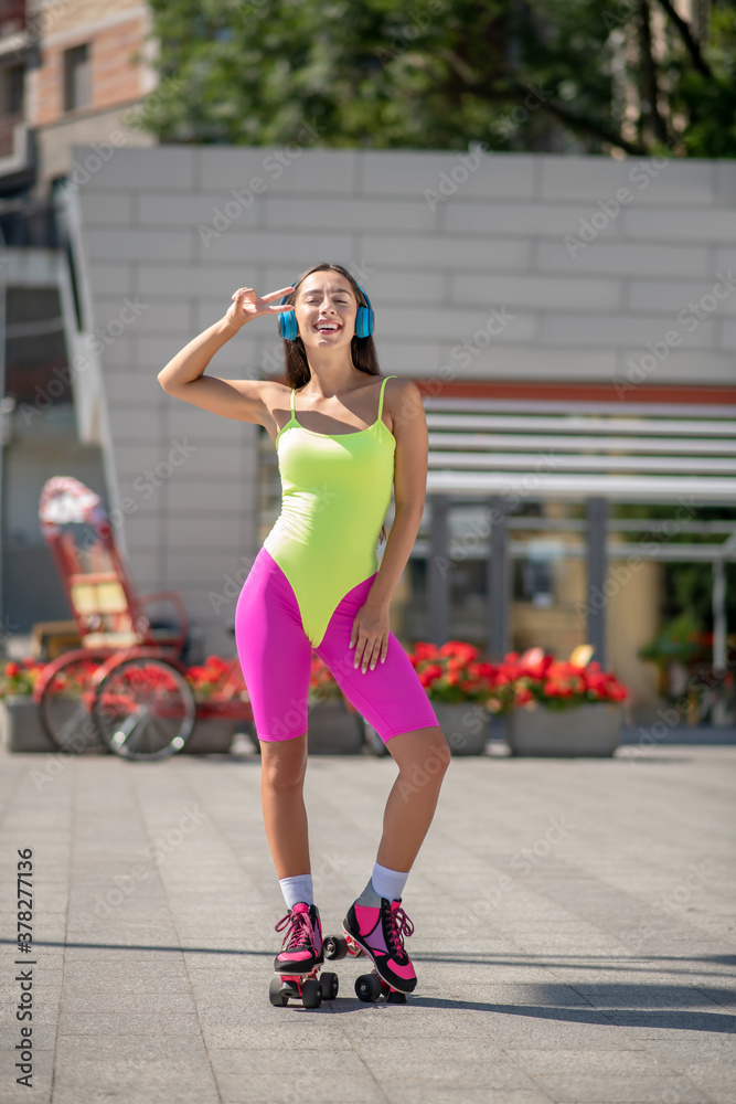 Girl in bright sportswear and roller-skates looking wonderful