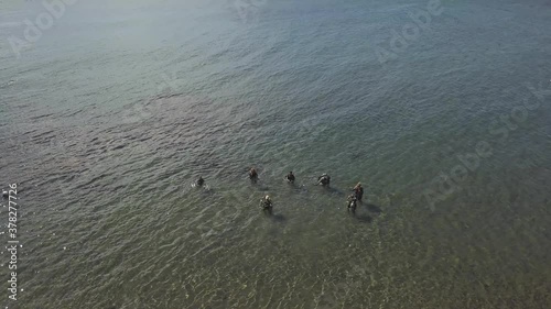Aerial: Group of scuba divers in training stand in a shallow clear ocean water. photo