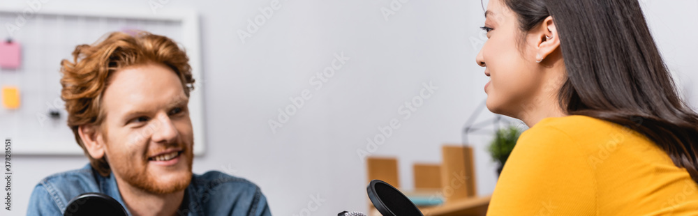 selective focus of young redhead radio host interviewing brunette asian woman in studio, horizontal image selective focus of young redhead radio host interviewing brunette asian woman in studio, horizontal image