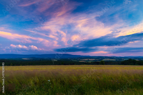 Warm summer sunset over fields and meadows