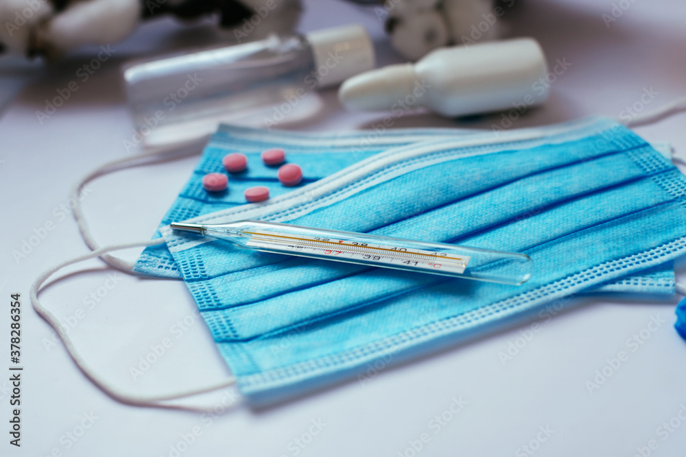 medical items placed on a white background, protective medical mask with ties, pills, thermometer. Health care concept. Prevention of coronavirus medical items placed on a white background, protective medical mask with ties, pills, thermometer. Health care concept. Prevention of coronavirus