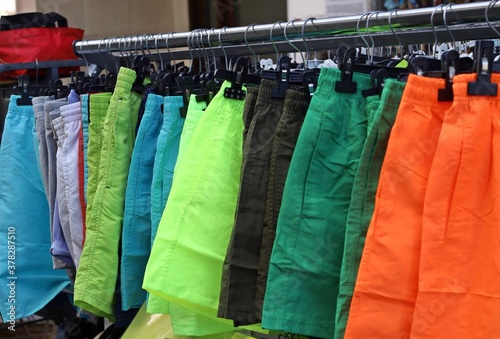 Men swimwears of different colors, shorts type, hanging on a clothing store hanger