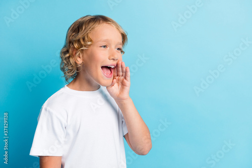 Photo of small boy screaming into empty space wear casual style clothes isolated over blue color background